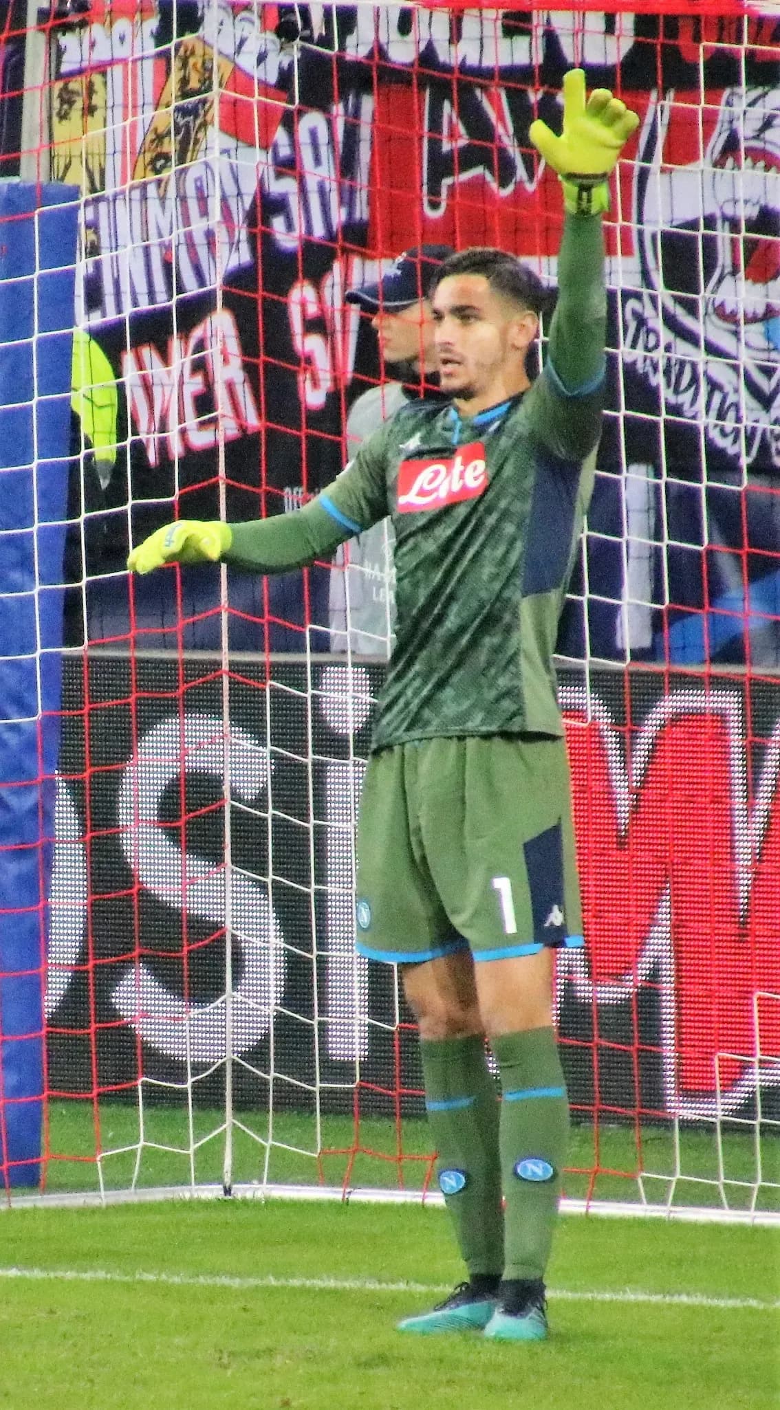 Alex Meret con la divisa del Napoli alza un braccio per dare indicazioni ai compagni durante una partita di Champions League.