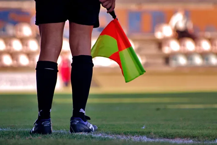 Un assistente arbitrale a bordo campo impugna la bandierina durante una partita